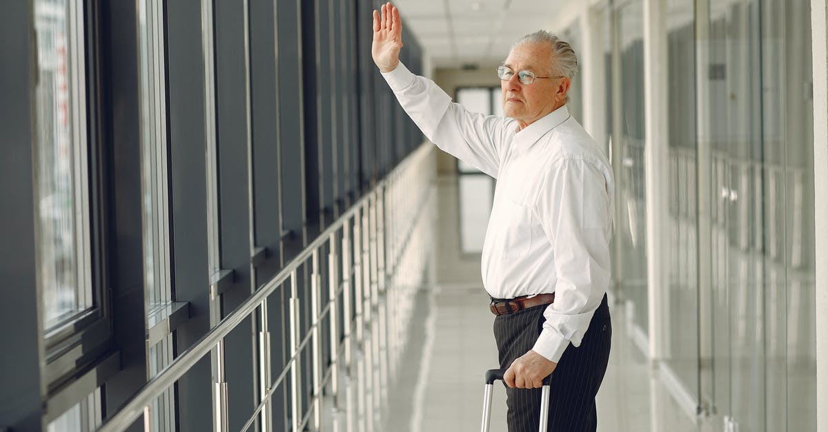 Can I transport a hairdryer in my hand luggage in Europe? - Side view of aged calm male in formal clothes with suitcase walking along modern airport hallway and waving goodbye while looking out glass wall Can I transport a hairdryer in my hand luggage in Europe? - Side view of aged calm male in formal clothes with suitcase walking along modern airport hallway and waving goodbye while looking out glass wall
