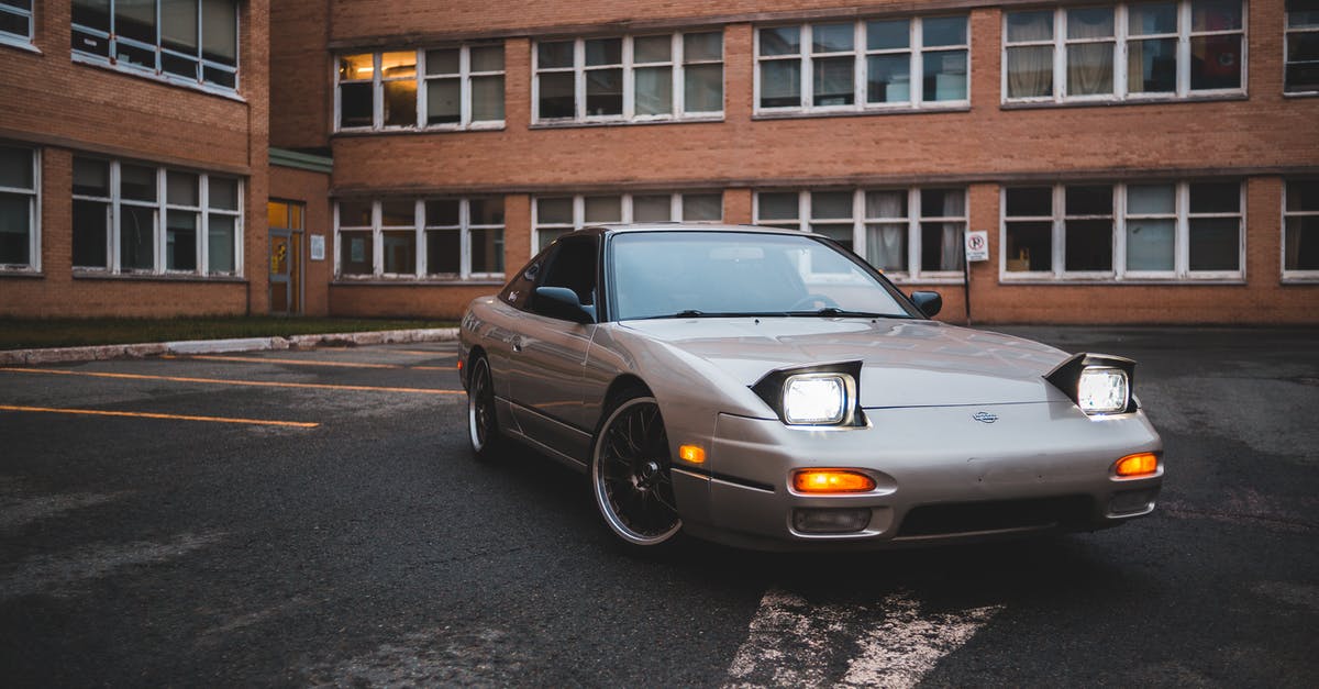 Can I travel with my old passport and have the new one sent to my destination? [closed] - Stylish silver automobile with indicators parked on concrete surface near brick stone building