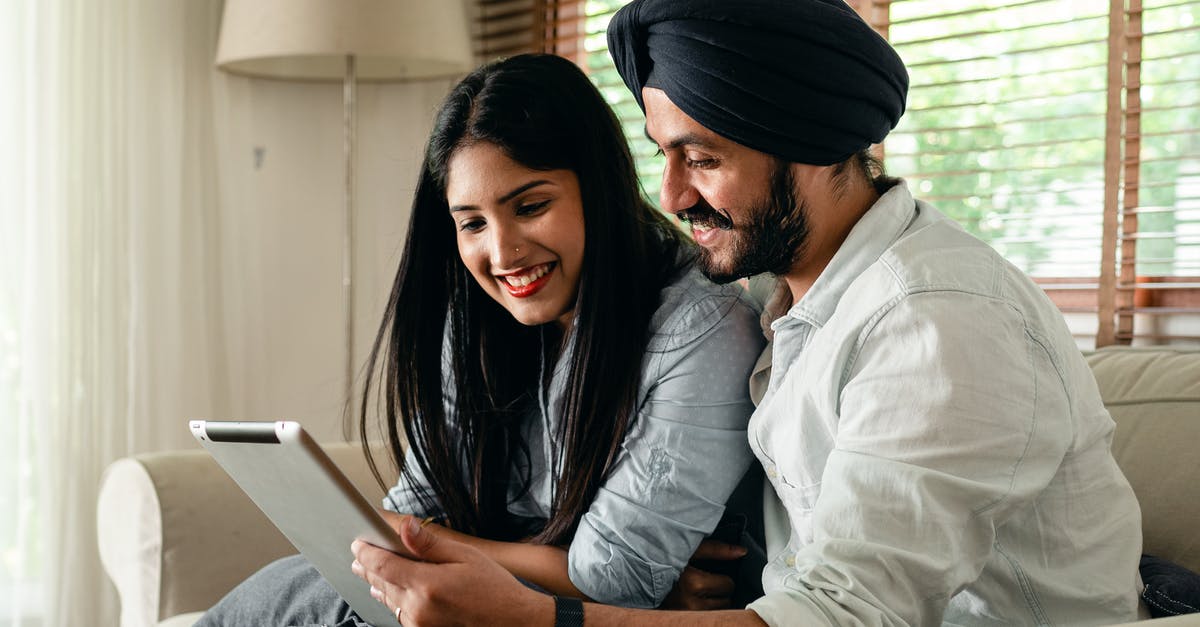 Can I use Indian electronic appliance in US - Calm ethnic couple browsing tablet and sitting in living room Can I use Indian electronic appliance in US - Calm ethnic couple browsing tablet and sitting in living room