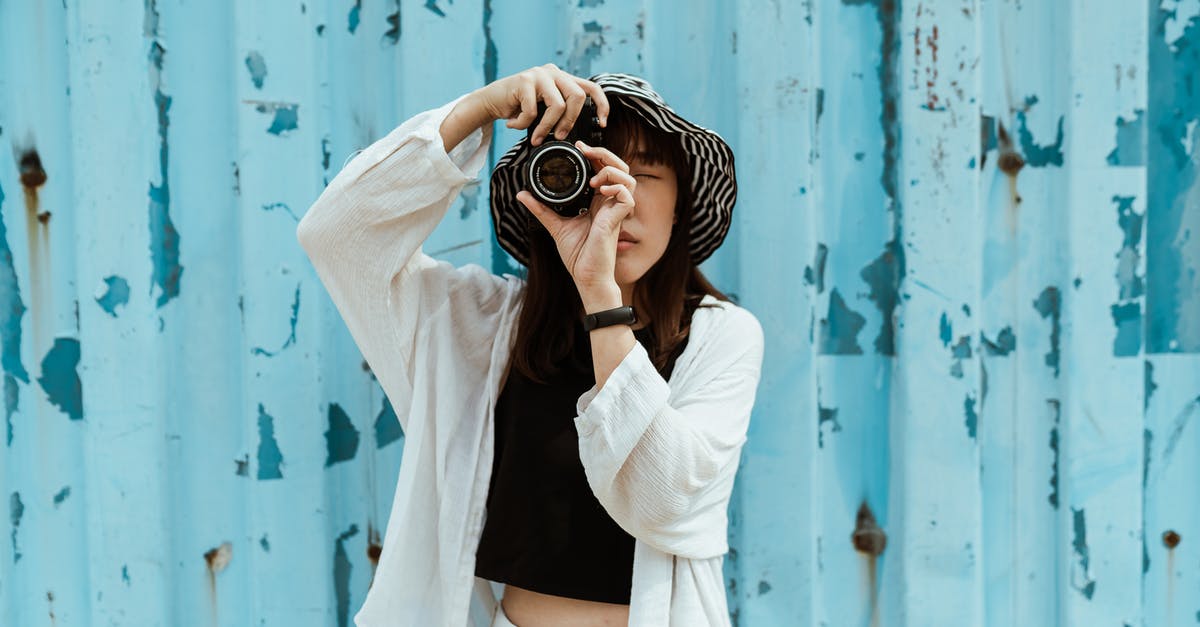 Can I use my type D visa to travel as a tourist? [closed] - Asian female tourist in striped hat and casual clothes taking photo on professional photo camera while standing with closed eyes near blue ribbed wall with spots on surface