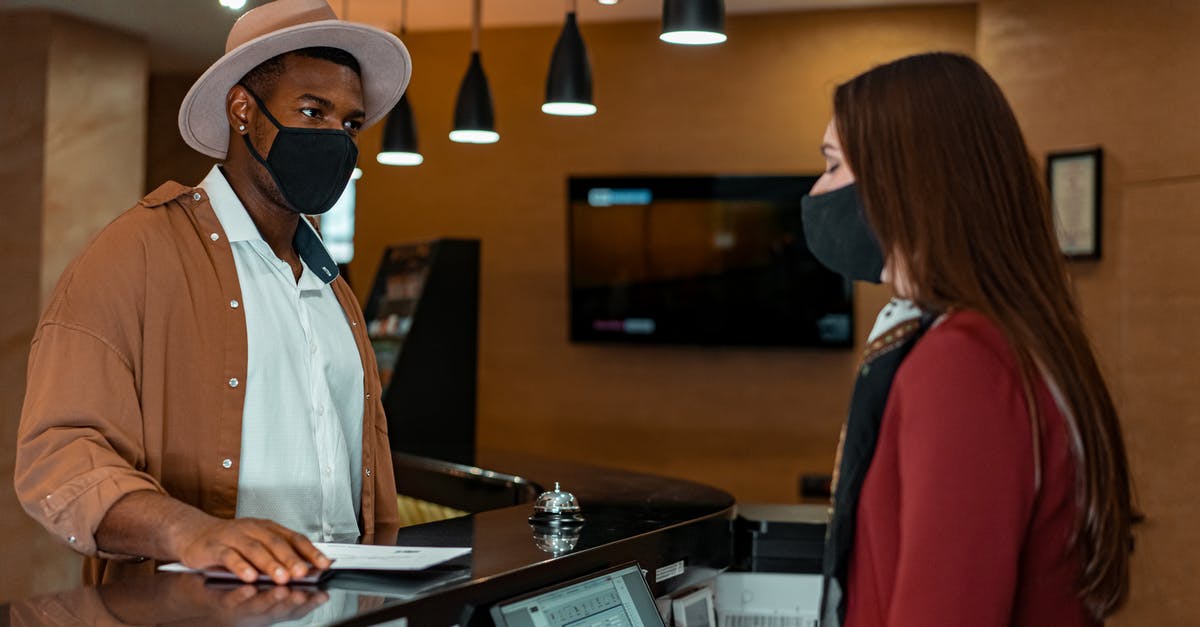 Can the person who books a hotel ask hotel for information regarding guests etc? - Woman in White Button Up Shirt and Red Coat Holding White Paper Can the person who books a hotel ask hotel for information regarding guests etc? - Woman in White Button Up Shirt and Red Coat Holding White Paper