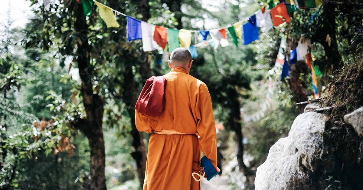 Can travellers see Buddhist temples in Saudi Arabia? - Monk Walking Near Buntings during Day Can travellers see Buddhist temples in Saudi Arabia? - Monk Walking Near Buntings during Day