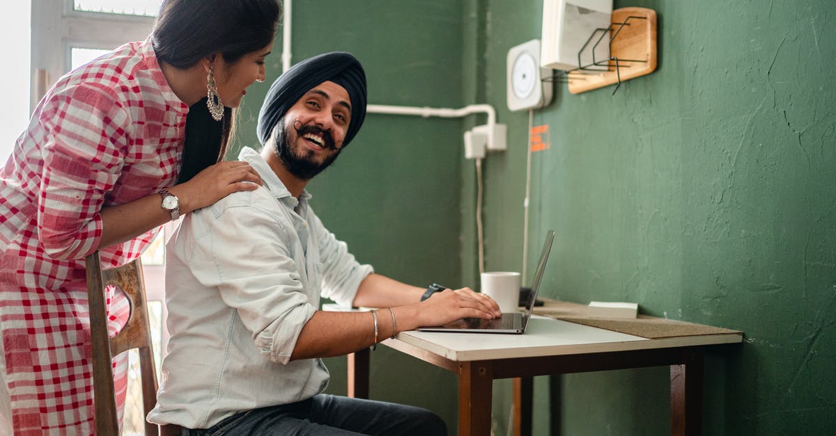 Can we go back to our home country then come back to the UK for six months? [closed] - Side view of ethnic male in casual clothes and hat using netbook at table while ethnic woman in casual clothes bending over and touching back of man