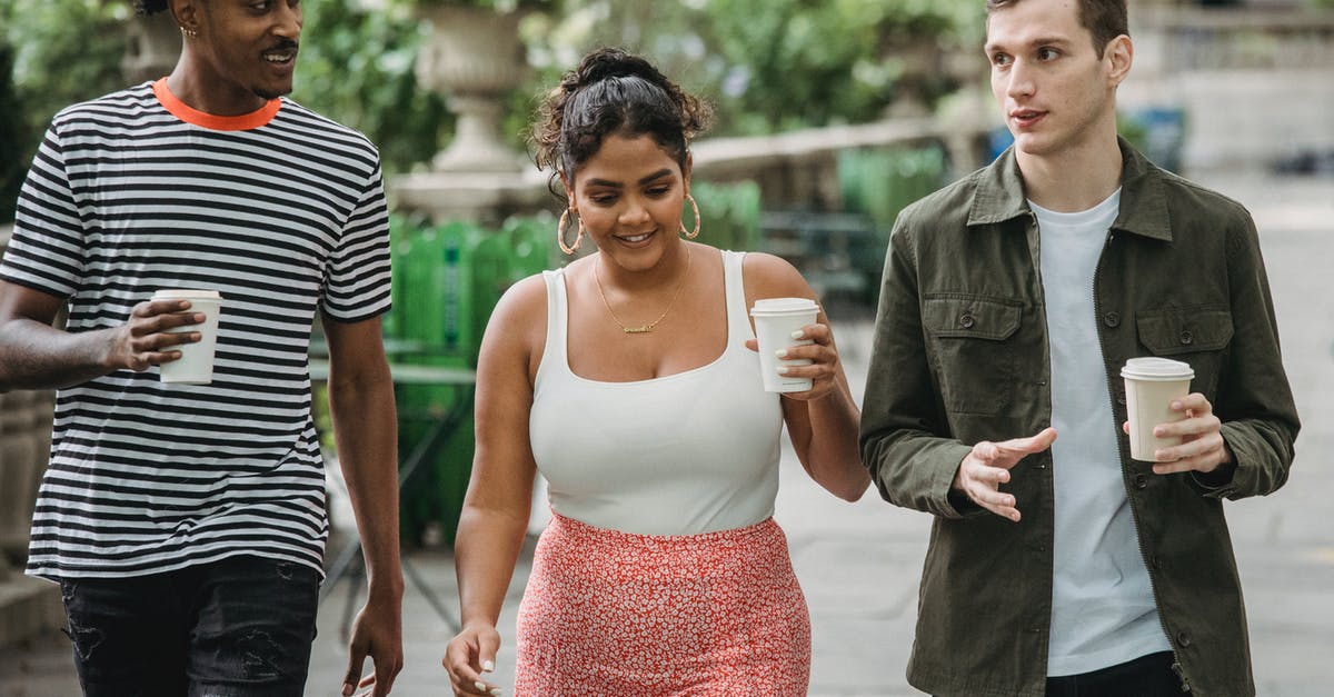 Can we share the Go Pass? - Joyful young multiethnic students in casual clothes discussing lessons while walking together in park with takeaway cups of coffee Can we share the Go Pass? - Joyful young multiethnic students in casual clothes discussing lessons while walking together in park with takeaway cups of coffee