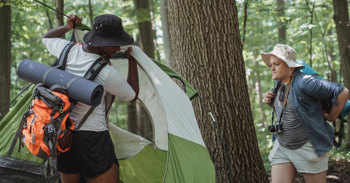 Can you freely camp along trails in Scotland? - Traveling men in shorts and hats setting up camping tent in woods Can you freely camp along trails in Scotland? - Traveling men in shorts and hats setting up camping tent in woods