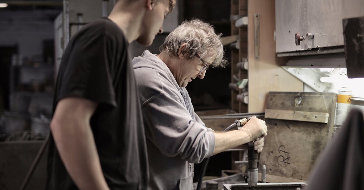 Can you look for a job in the UK without a visa? - Side view of senior artisan in eyeglasses handling detail in workshop while apprentice looking at process Can you look for a job in the UK without a visa? - Side view of senior artisan in eyeglasses handling detail in workshop while apprentice looking at process