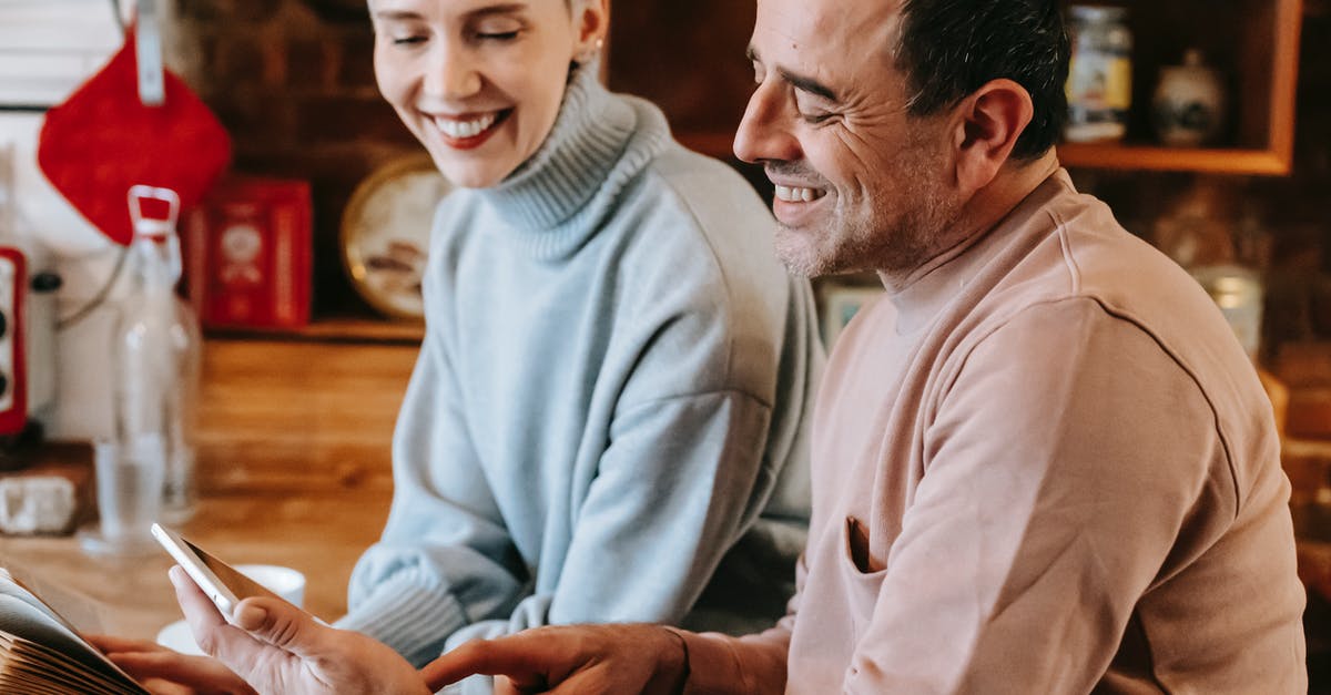 Can you please share the link to book appointment at italian consulate in san francisco [closed] - Side view of crop positive multiracial spouses in casual clothes smiling while watching video on tablet sitting at wooden table in kitchen