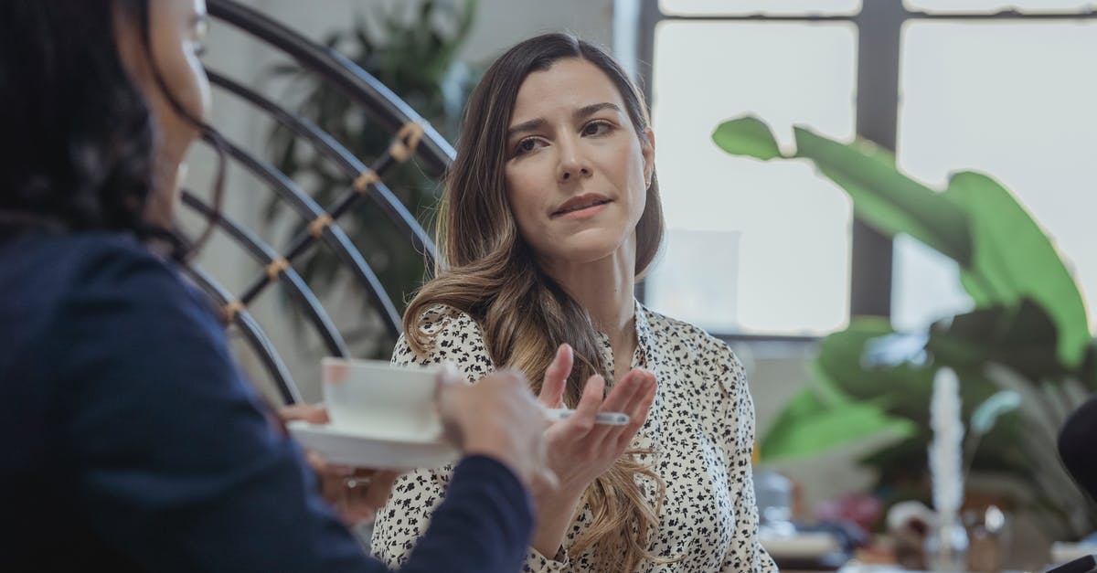 Can you work remote in Italy for a UK based company with just a tourist visa? - Woman discussing work with black colleague drinking coffee Can you work remote in Italy for a UK based company with just a tourist visa? - Woman discussing work with black colleague drinking coffee