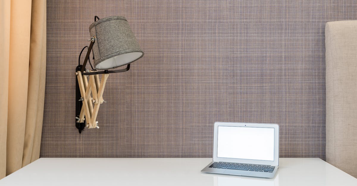 Cancel a Hotel Room After Checking in Online - Interior of workplace with opened netbook on white table near wall with lamp Cancel a Hotel Room After Checking in Online - Interior of workplace with opened netbook on white table near wall with lamp