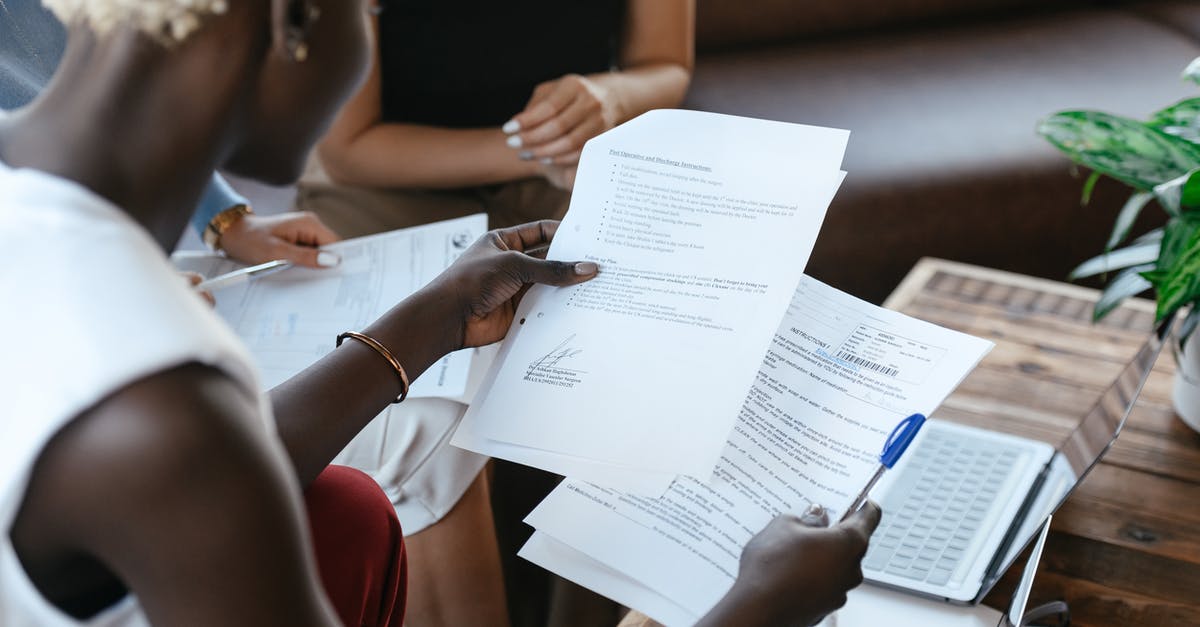 Cancelling a Prepaid Contract (US) from Germany - From above of crop anonymous African American female comparing data in papers at table of office Cancelling a Prepaid Contract (US) from Germany - From above of crop anonymous African American female comparing data in papers at table of office