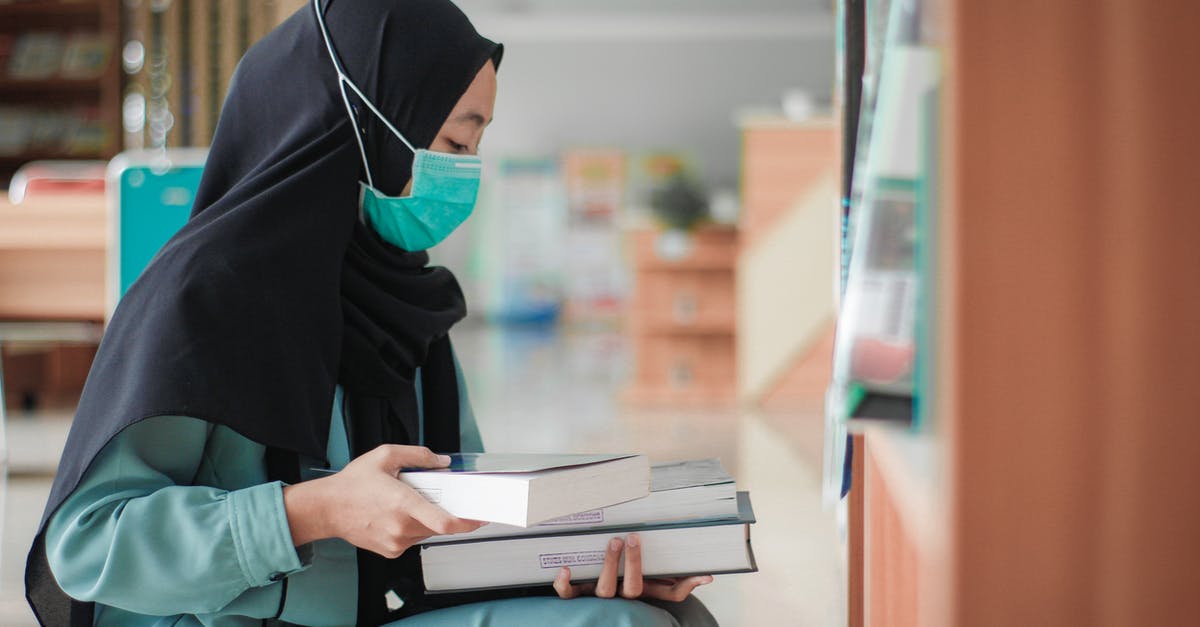 Cancelling booking on Booking.com due to COVID-19 - Woman Wearing Face Mask Holding a Book Cancelling booking on Booking.com due to COVID-19 - Woman Wearing Face Mask Holding a Book