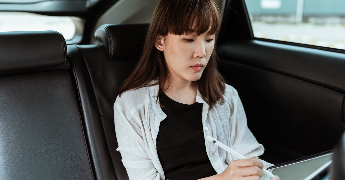 Cancelling Schengen Student Visa Application - Concentrated Asian female in casual clothes working on modern tablet with stylus while riding in car backseat Cancelling Schengen Student Visa Application - Concentrated Asian female in casual clothes working on modern tablet with stylus while riding in car backseat