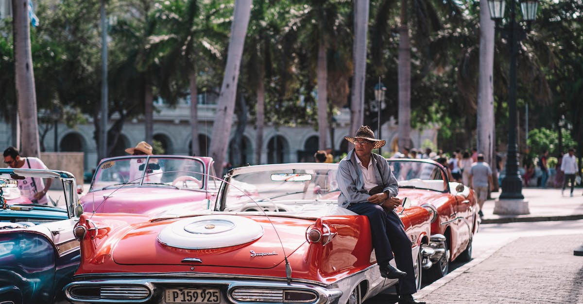 Car rental in Cuba - A Man Sitting on Red Vintage Car Car rental in Cuba - A Man Sitting on Red Vintage Car