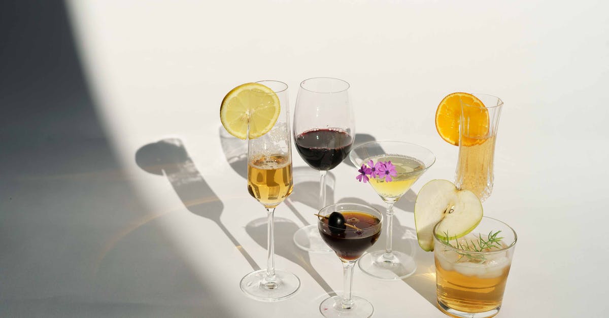 Carrying Liquor from Heathrow to Bangalore via Abu Dhabi - High angle of crystal glasses filled with champagne red wine Manhattan with olive on toothpick martini near pear calvados in white studio Carrying Liquor from Heathrow to Bangalore via Abu Dhabi - High angle of crystal glasses filled with champagne red wine Manhattan with olive on toothpick martini near pear calvados in white studio