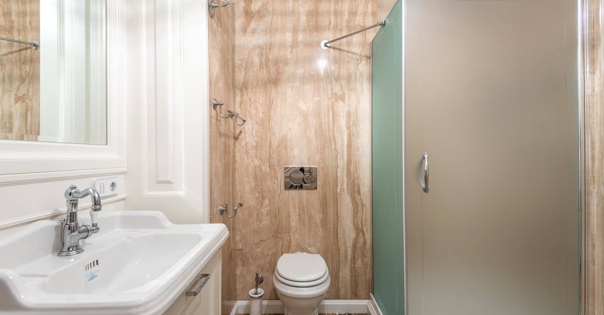 Cast iron pot in cabin luggage? - Interior of bathroom with wall mounted toilet and shower cabin at tiled wall near clean sink under bright lighting Cast iron pot in cabin luggage? - Interior of bathroom with wall mounted toilet and shower cabin at tiled wall near clean sink under bright lighting