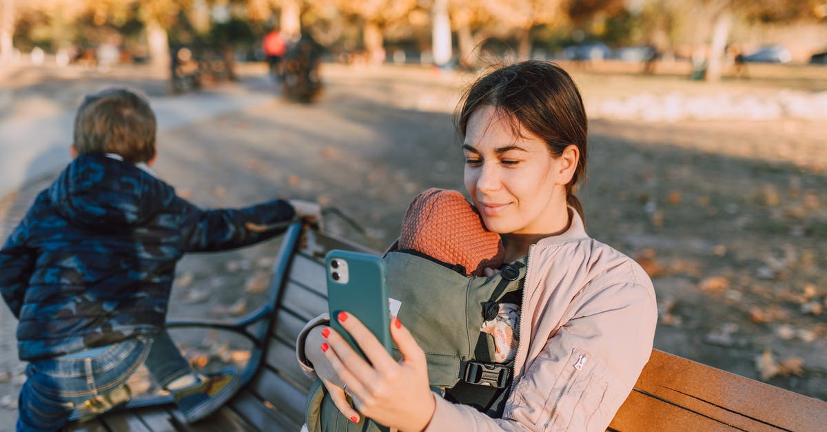 Cellphone carriers in Europe - A Woman Sitting on a Wooden Bench at the Park while Using Her Mobile Phone Cellphone carriers in Europe - A Woman Sitting on a Wooden Bench at the Park while Using Her Mobile Phone