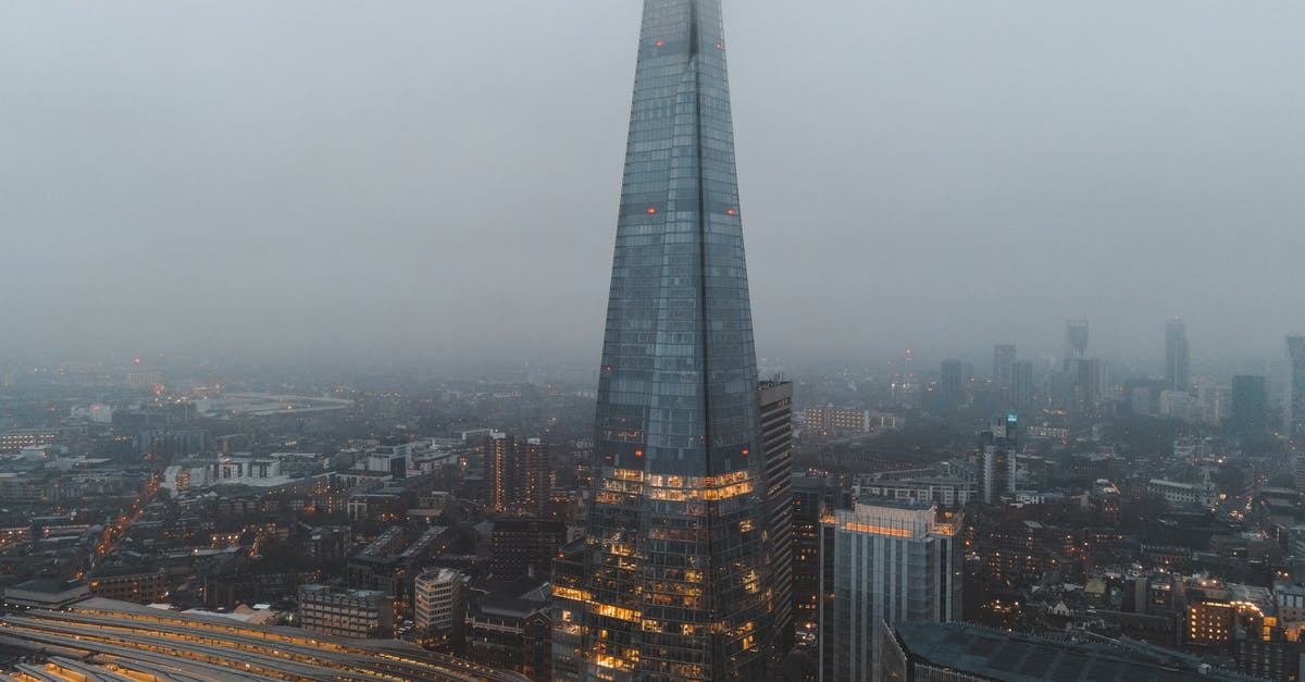 Central districts in London? - Aerial view of London city located in England with modern buildings and Shard skyscraper near railroads under gray cloudy sky in hazy day in daytime Central districts in London? - Aerial view of London city located in England with modern buildings and Shard skyscraper near railroads under gray cloudy sky in hazy day in daytime
