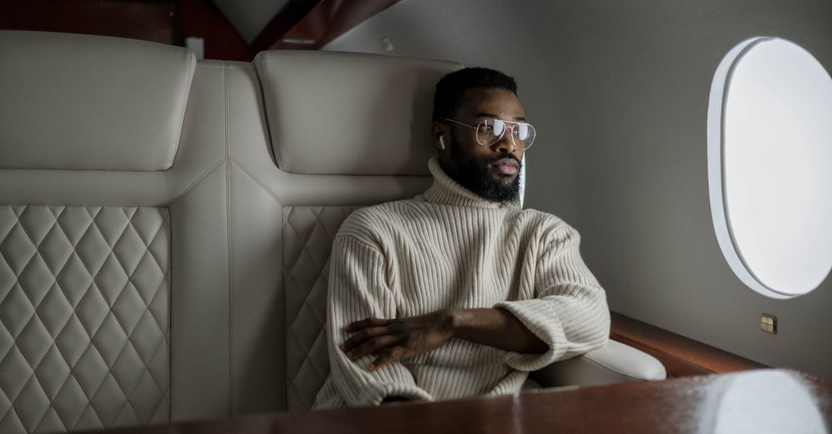 Changing a passenger on a Lufthansa flight - Man in White Sweater Sitting on White Leather Couch Changing a passenger on a Lufthansa flight - Man in White Sweater Sitting on White Leather Couch