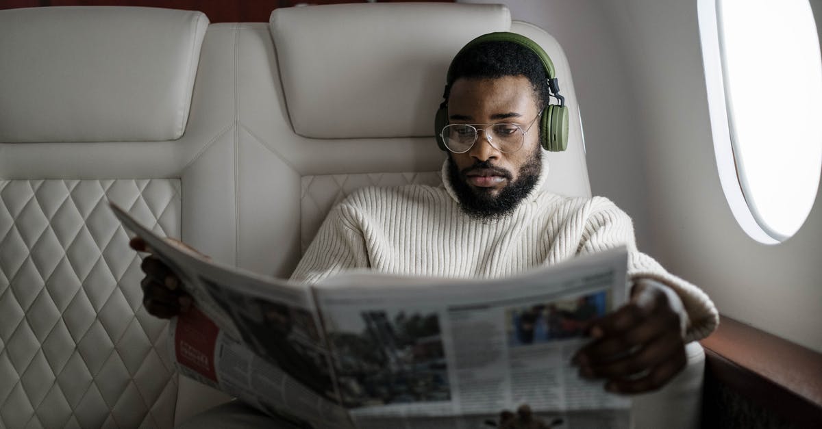 Changing a passenger on a Lufthansa flight - A Man with Eyeglasses Reading a Newspaper Changing a passenger on a Lufthansa flight - A Man with Eyeglasses Reading a Newspaper