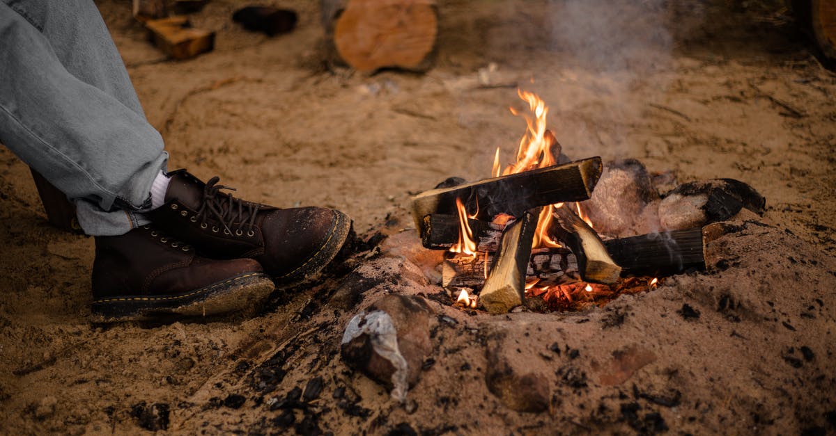 Cheap camping in southern Brazil - Burning Campfire and Feet of a Person in Hiking Boots Cheap camping in southern Brazil - Burning Campfire and Feet of a Person in Hiking Boots