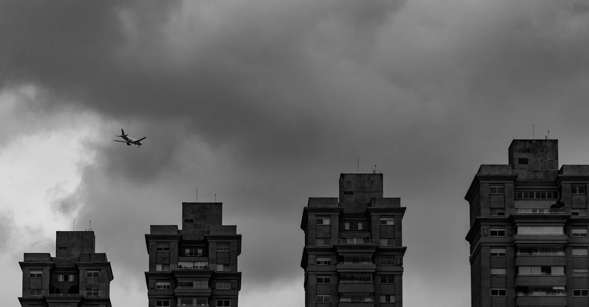 Cheapest flight "from any city" - Aircraft flying in thick clouds above city buildings Cheapest flight "from any city" - Aircraft flying in thick clouds above city buildings