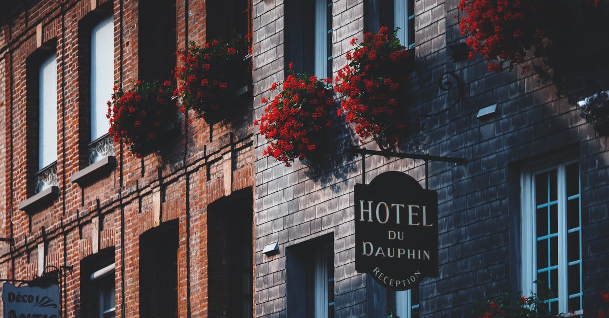 Cheapest hotel in Europe - Facade of modern masonry building decorated with red flowers Cheapest hotel in Europe - Facade of modern masonry building decorated with red flowers