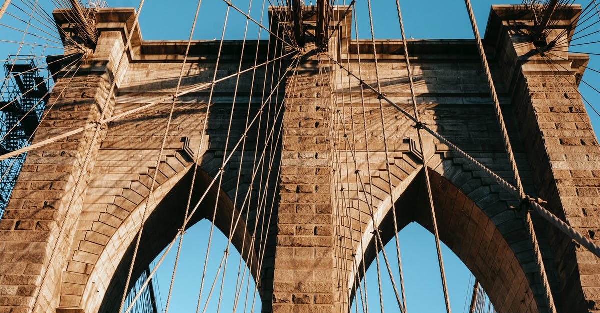Cheapest way from USA to Venezuela? - Low angle of famous Brooklyn brick arches with ropes on top of bridge in metropolis Cheapest way from USA to Venezuela? - Low angle of famous Brooklyn brick arches with ropes on top of bridge in metropolis