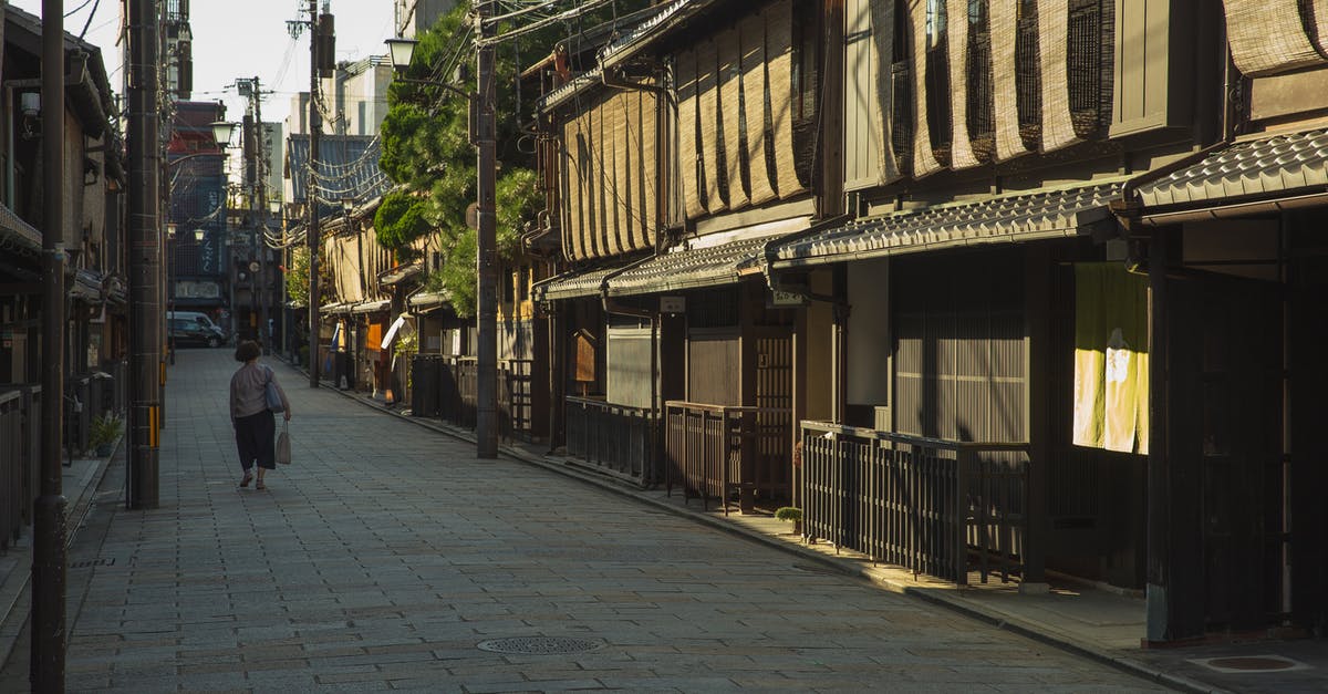 Cheapest way to travel from Osaka Kansai airport to Kyoto and back? - Unrecognizable woman walking near traditional houses in Japan Cheapest way to travel from Osaka Kansai airport to Kyoto and back? - Unrecognizable woman walking near traditional houses in Japan