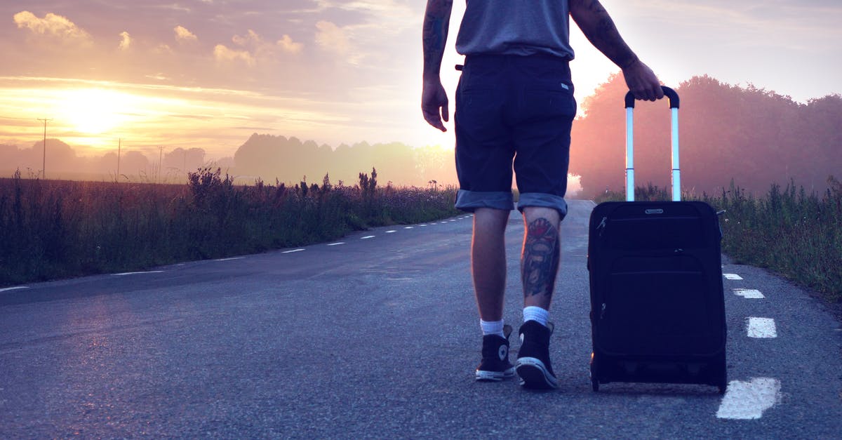 Checking luggage all the way through? - Man With Luggage on Road during Sunset Checking luggage all the way through? - Man With Luggage on Road during Sunset