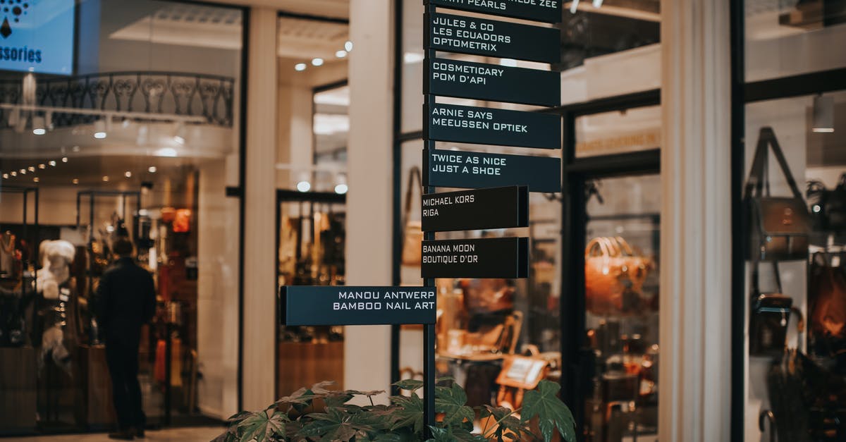 Checking-in bags to different destinations when flying with a layover - Signboard located near store with various goods Checking-in bags to different destinations when flying with a layover - Signboard located near store with various goods