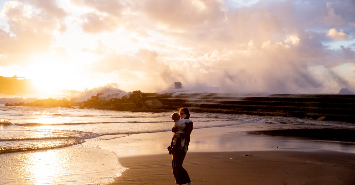 Child travel consent for Lima, Peru - Woman Standing on Seashore Carrying Her Child during Sunset Child travel consent for Lima, Peru - Woman Standing on Seashore Carrying Her Child during Sunset