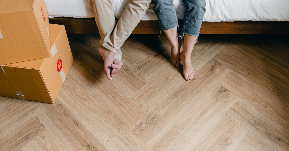 Clarify if new DS-160 is needed if change venue from London to Belfast after transmitting - Unrecognizable barefoot man and woman sitting on bed near carton boxes while relaxing from unboxing belongings during relocation in new flat