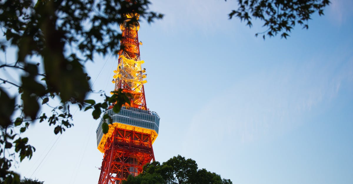 Communicating in Tokyo without Japanese - From below of colorful high metal television tower with observation deck near tree branches in Tokyo Communicating in Tokyo without Japanese - From below of colorful high metal television tower with observation deck near tree branches in Tokyo
