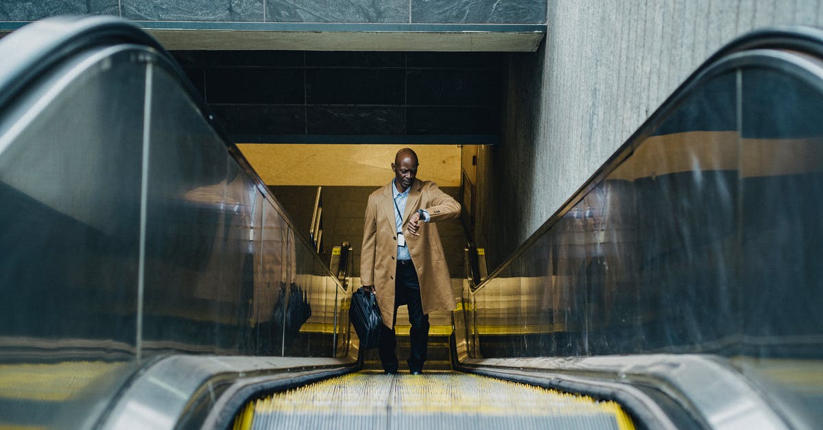 Compensation in case of delay from the EU via Turkish Airlines - Contemplative black businessman riding escalator and looking at wristwatch Compensation in case of delay from the EU via Turkish Airlines - Contemplative black businessman riding escalator and looking at wristwatch