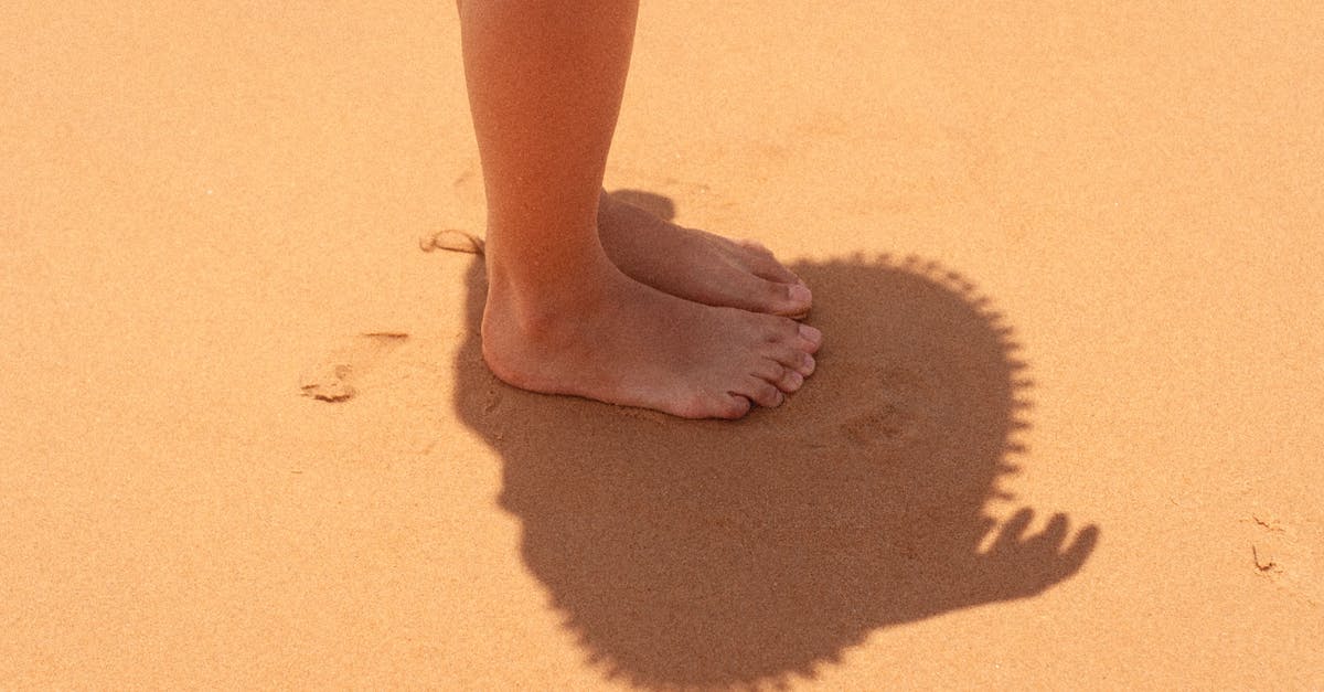 Completing second leg of travel on a different day - Faceless person on sandy coast in sunlight Completing second leg of travel on a different day - Faceless person on sandy coast in sunlight