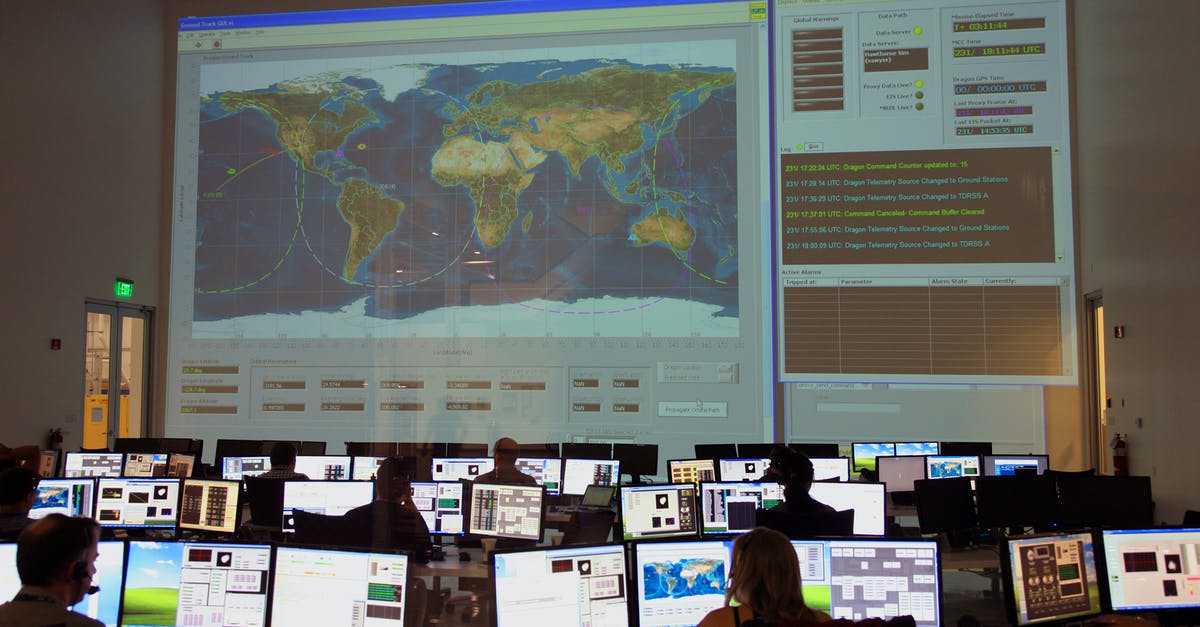 Connecting flight in Tel Aviv - Back view of unrecognizable employees working on computers in flight control room with big interactive map on wall and analyzing data Connecting flight in Tel Aviv - Back view of unrecognizable employees working on computers in flight control room with big interactive map on wall and analyzing data