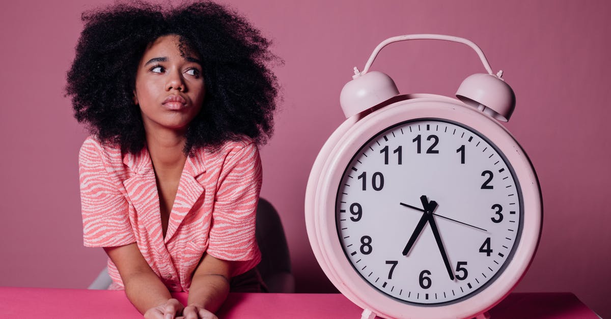 Connecting flight wait time 11 hours 20 minutes - is it possible to exit to see Vancouver? - Woman in Pink Long Sleeve Shirt Sitting Beside White and Pink Alarm Clock Connecting flight wait time 11 hours 20 minutes - is it possible to exit to see Vancouver? - Woman in Pink Long Sleeve Shirt Sitting Beside White and Pink Alarm Clock