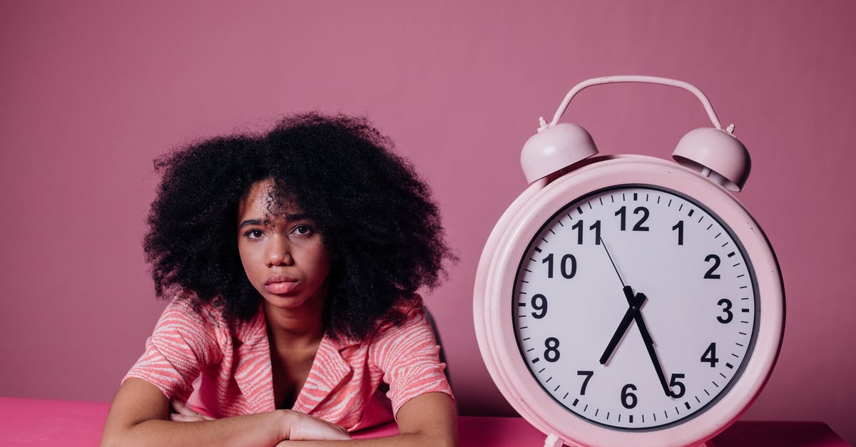 Connecting flight wait time 11 hours 20 minutes - is it possible to exit to see Vancouver? - Woman Looking Bored Beside a Big Alarm Clock Connecting flight wait time 11 hours 20 minutes - is it possible to exit to see Vancouver? - Woman Looking Bored Beside a Big Alarm Clock