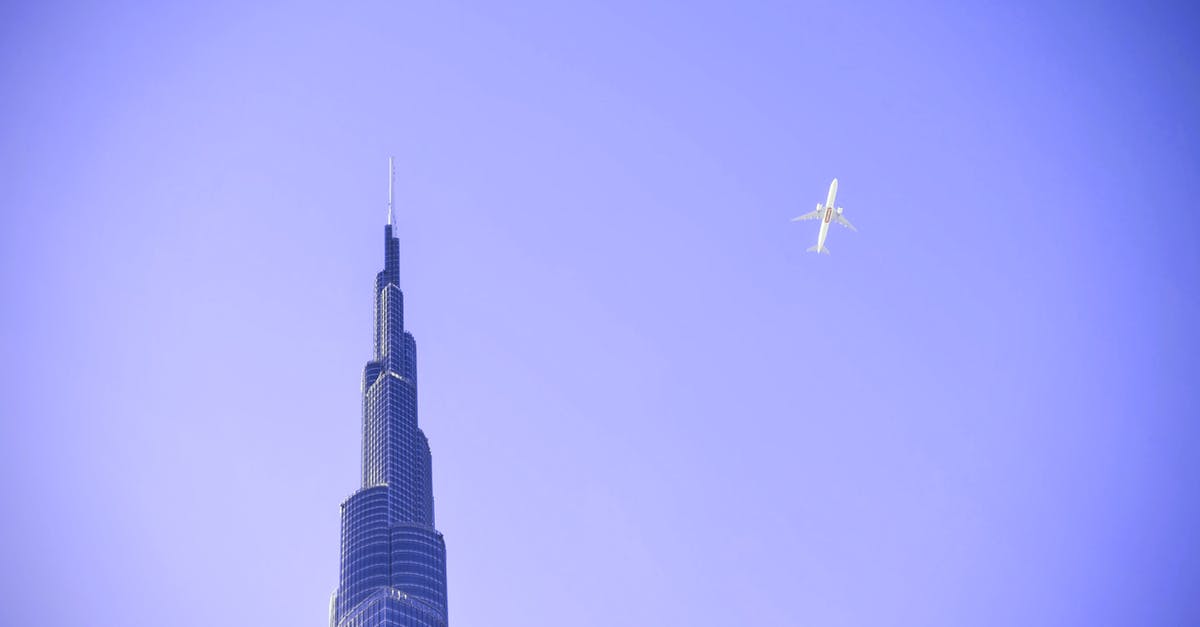 Connecting in Dubai on different airlines - White Airplane Flying over Building Connecting in Dubai on different airlines - White Airplane Flying over Building