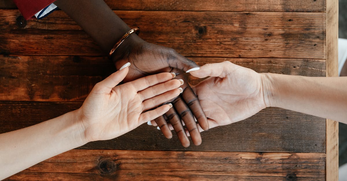 Connecting in Toronto on different airlines - Diverse women stacking hands on wooden table Connecting in Toronto on different airlines - Diverse women stacking hands on wooden table