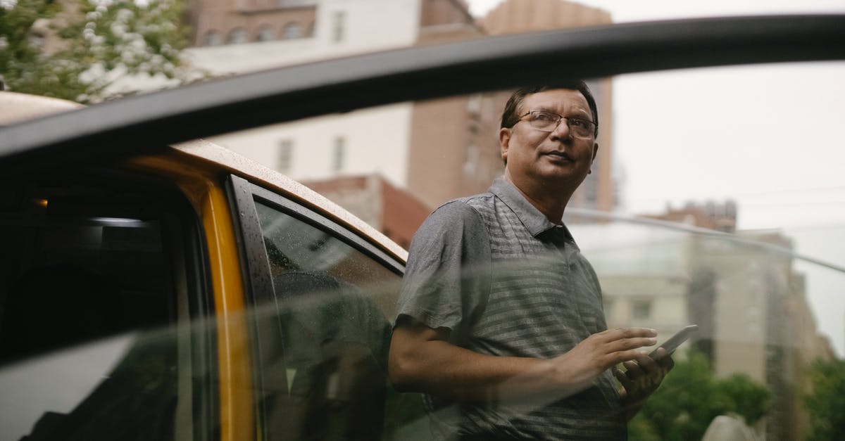Connection from Mexico through Dallas onto Canada - Ethnic man leaning on taxi with smartphone Connection from Mexico through Dallas onto Canada - Ethnic man leaning on taxi with smartphone