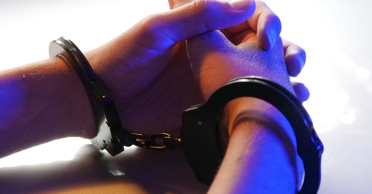 Consequences of being arrested by mistake in the USA - Person Wearing Black Watch Holding Brown Wooden Table Consequences of being arrested by mistake in the USA - Person Wearing Black Watch Holding Brown Wooden Table