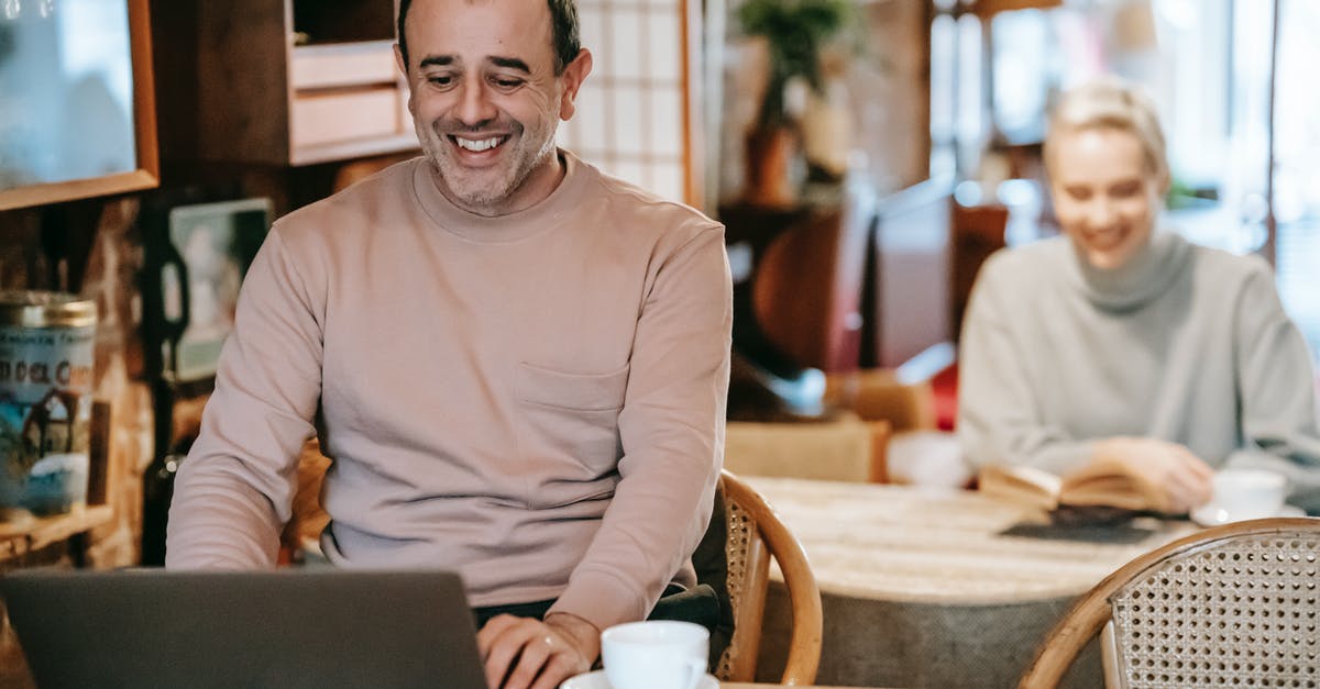 Cover letter for spouse travelling with husband on business visa - Cheerful middle aged ethnic man smiling while working remotely on laptop near positive wife reading book and drinking coffee Cover letter for spouse travelling with husband on business visa - Cheerful middle aged ethnic man smiling while working remotely on laptop near positive wife reading book and drinking coffee