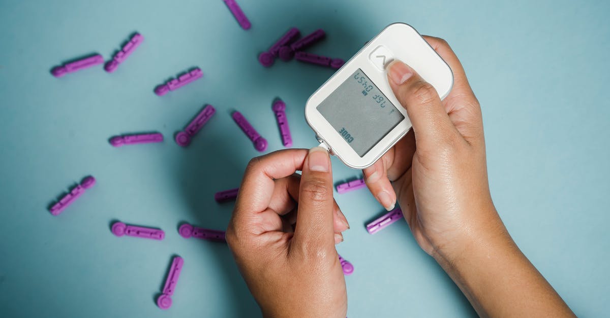 COVID-19 - show negative PCR test results at boarding at layover or at check-in in starting airport? - Top view of crop anonymous female diabetic measuring blood sugar with glucometer over scattered lancets
