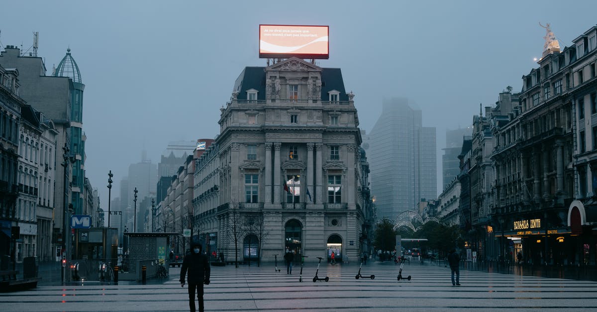 COVID-19 Mix-and-match (AstraZeneca & BioNTech/Pfizer): Am I considered vaccinated for travel in Europe? - Unrecognizable pedestrians in face masks walking on city square near aged buildings against foggy sky in evening in Brussels COVID-19 Mix-and-match (AstraZeneca & BioNTech/Pfizer): Am I considered vaccinated for travel in Europe? - Unrecognizable pedestrians in face masks walking on city square near aged buildings against foggy sky in evening in Brussels