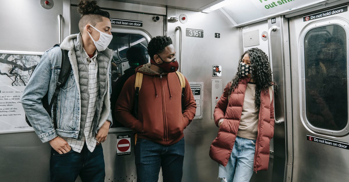 Covid Travel Insurance - Diverse passengers speaking while travelling on subway Covid Travel Insurance - Diverse passengers speaking while travelling on subway