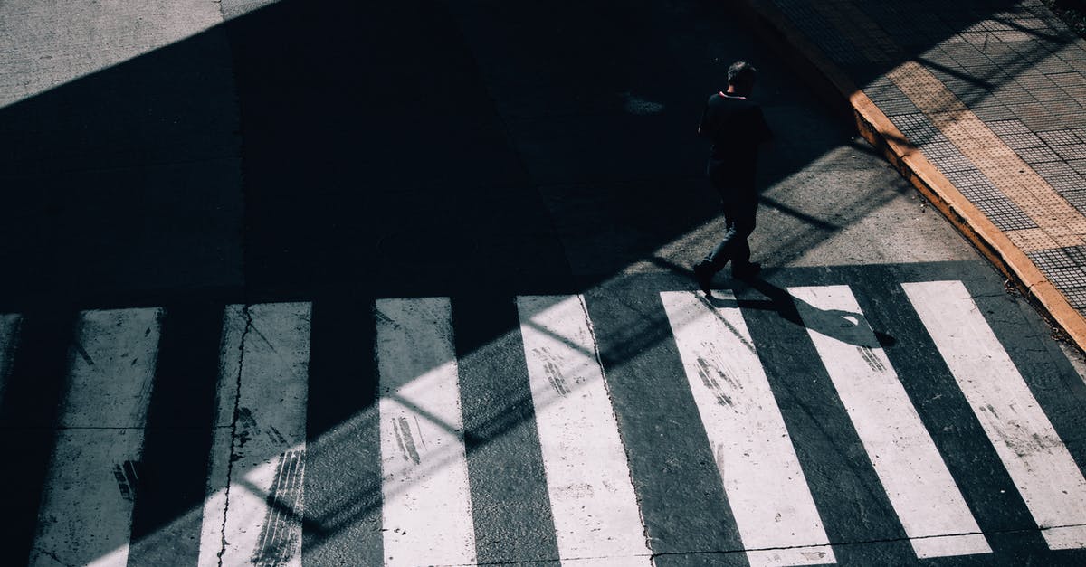 Cross mark on a visa stamp - Bahamas - From above full body of anonymous man in shadow strolling on crosswalk of road in sunny day Cross mark on a visa stamp - Bahamas - From above full body of anonymous man in shadow strolling on crosswalk of road in sunny day
