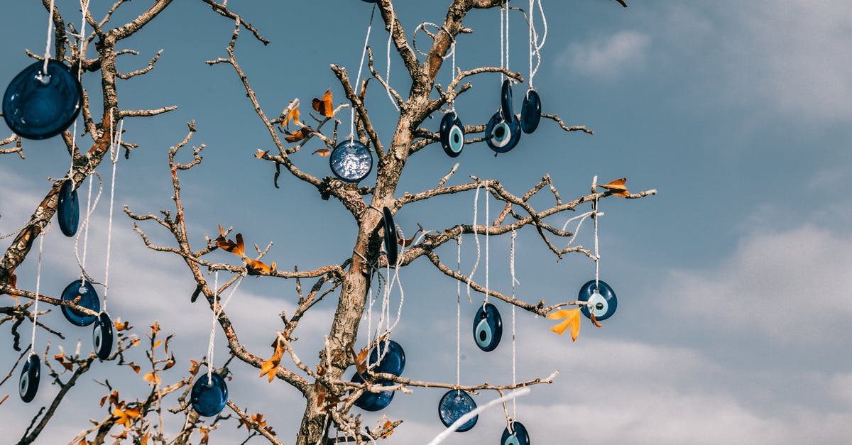 Crossing from Georgia into Turkey - From below of traditional blue eye shaped nazar amulets protecting form evil eye hanging on leafless tree branches against cloudy blue sky in Cappadocia Crossing from Georgia into Turkey - From below of traditional blue eye shaped nazar amulets protecting form evil eye hanging on leafless tree branches against cloudy blue sky in Cappadocia