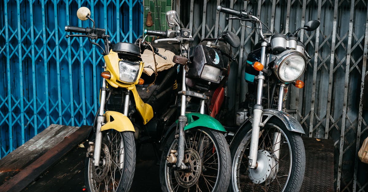 Crossing from Thailand to Cambodia with a motorbike scooter registered in Thailand - Yellow and Black Motorcycle Parked Beside Blue Metal Fence Crossing from Thailand to Cambodia with a motorbike scooter registered in Thailand - Yellow and Black Motorcycle Parked Beside Blue Metal Fence