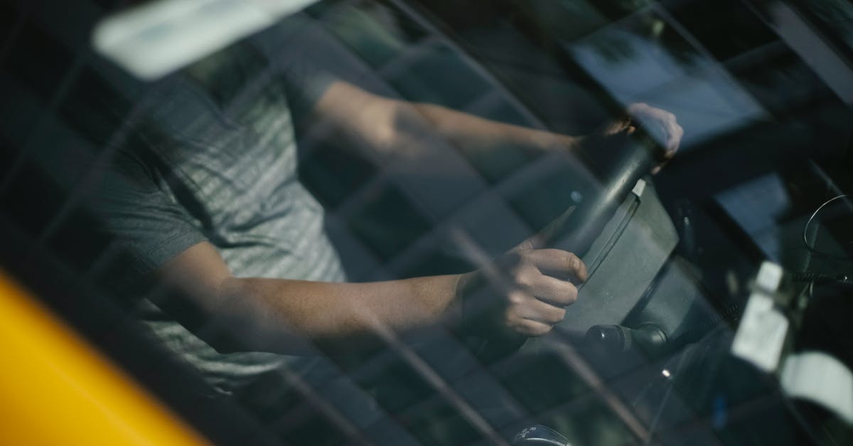 Crossing from USA to Canada (or vice versa) by car, without going through a standard border control - Through glass of windshield of ethnic crop male driver in cab while working in city Crossing from USA to Canada (or vice versa) by car, without going through a standard border control - Through glass of windshield of ethnic crop male driver in cab while working in city